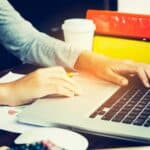 Przycięte ręce bizneswoman używającej laptopa przy biurku
