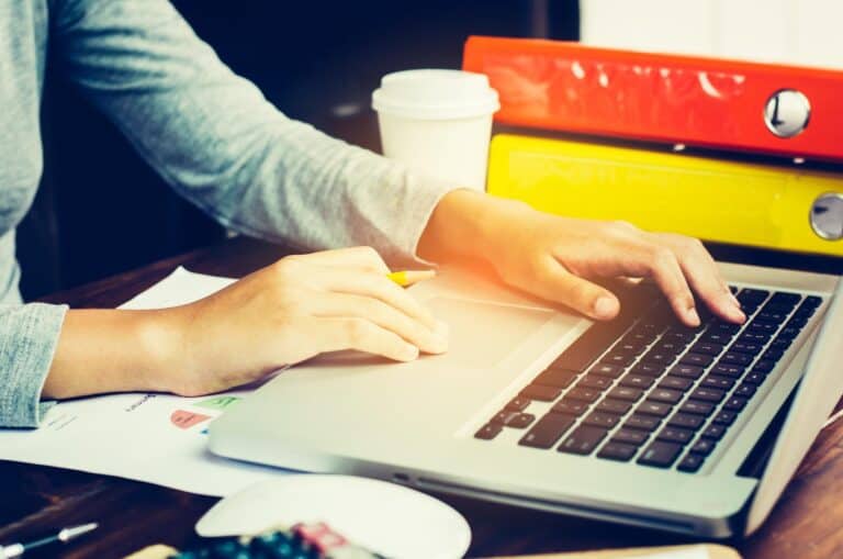 Przycięte ręce bizneswoman używającej laptopa przy biurku