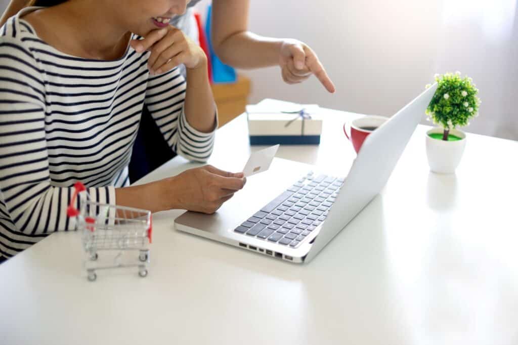 Środkowa część kobiety używającej telefonu komórkowego przy stole