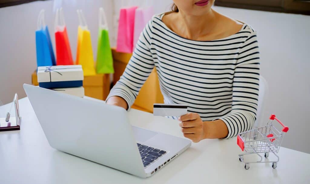 Środkowa sekcja bizneswoman trzymając kartę kredytową podczas korzystania z laptopa na stole