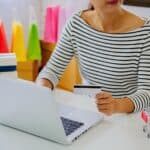 Środkowa sekcja bizneswoman trzymając kartę kredytową podczas korzystania z laptopa na stole