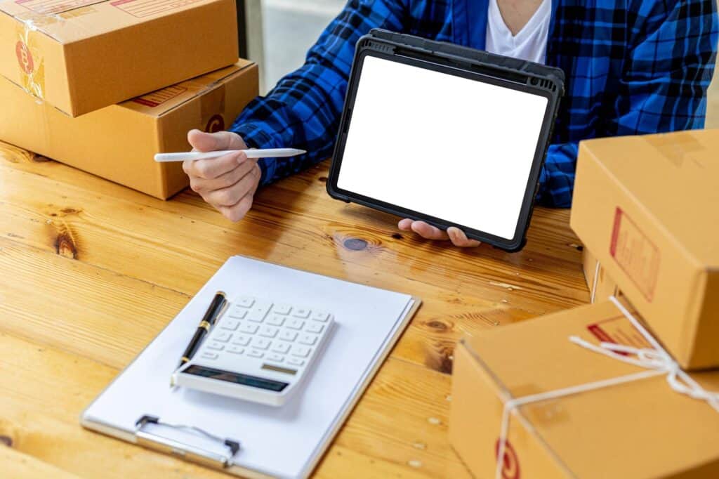 Man holding a tablet with a white screen for texting, He owns an online store, He packs and ships through a private transport company. Online selling and online shopping concepts.