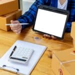 Man holding a tablet with a white screen for texting, He owns an online store, He packs and ships through a private transport company. Online selling and online shopping concepts.