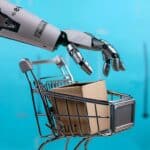 Zdjęcie ręki robota popychającego pusty wózek z kartonowymi pudełkami na niebieskim tle