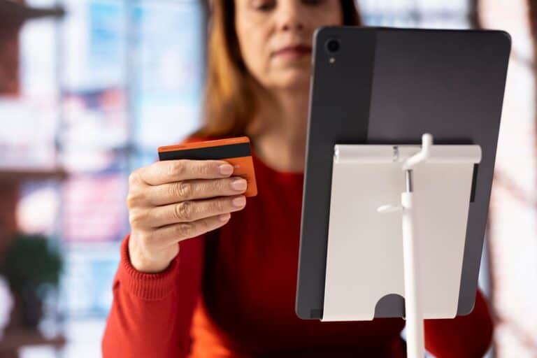 Przypadkowa kobieta trzymająca kartę do sprawdzenia salda finansowego przed zakupem czegoś