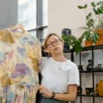 A woman showcasing a colorful dress in a stylish boutique setting, ideal for online selling.